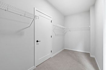 the closet in a bedroom with white walls and a white closet door